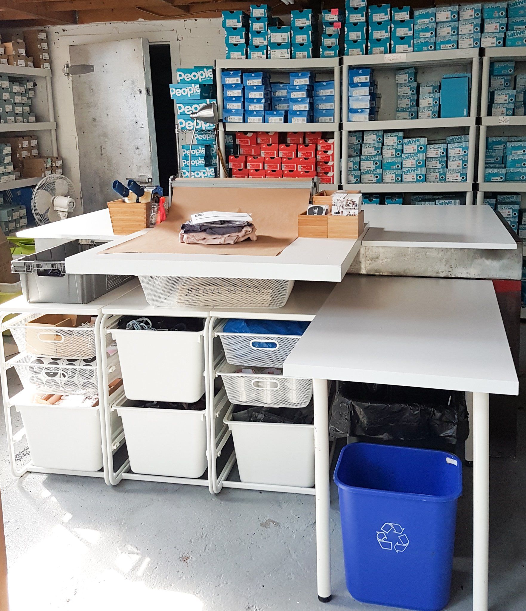A blue trash can sits next to a table in a store