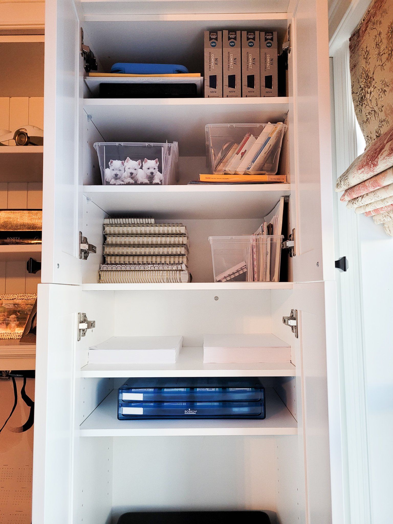 A white cabinet with a blue box on the bottom shelf