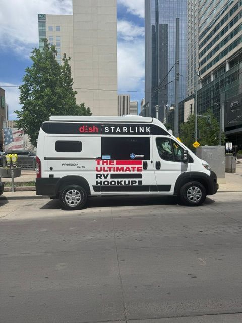 White Starlink service van with “HVAC” lettering parked on a city street among tall buildings.