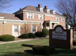 Brick building with sign reading McDow Funeral Home, set behind trimmed shrubs and a lawn
