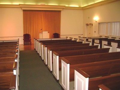 Empty church sanctuary with wooden pews, green carpet, and a pulpit at the front