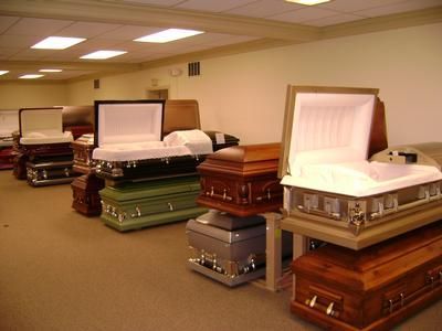 Open caskets displayed in a funeral home showroom, with several polished wood finishes.