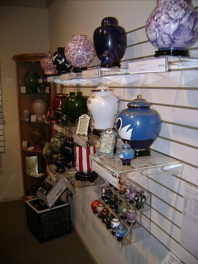 Store display of decorative glass and ceramic vases on shelves and tables, including a blue lidded jar.