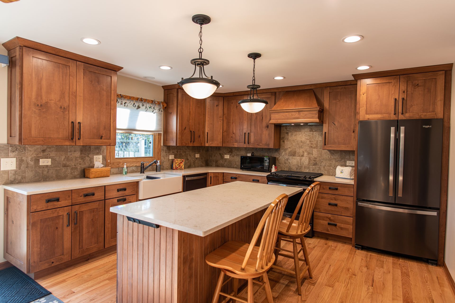 A kitchen with wooden cabinets , stainless steel appliances , and a large island.