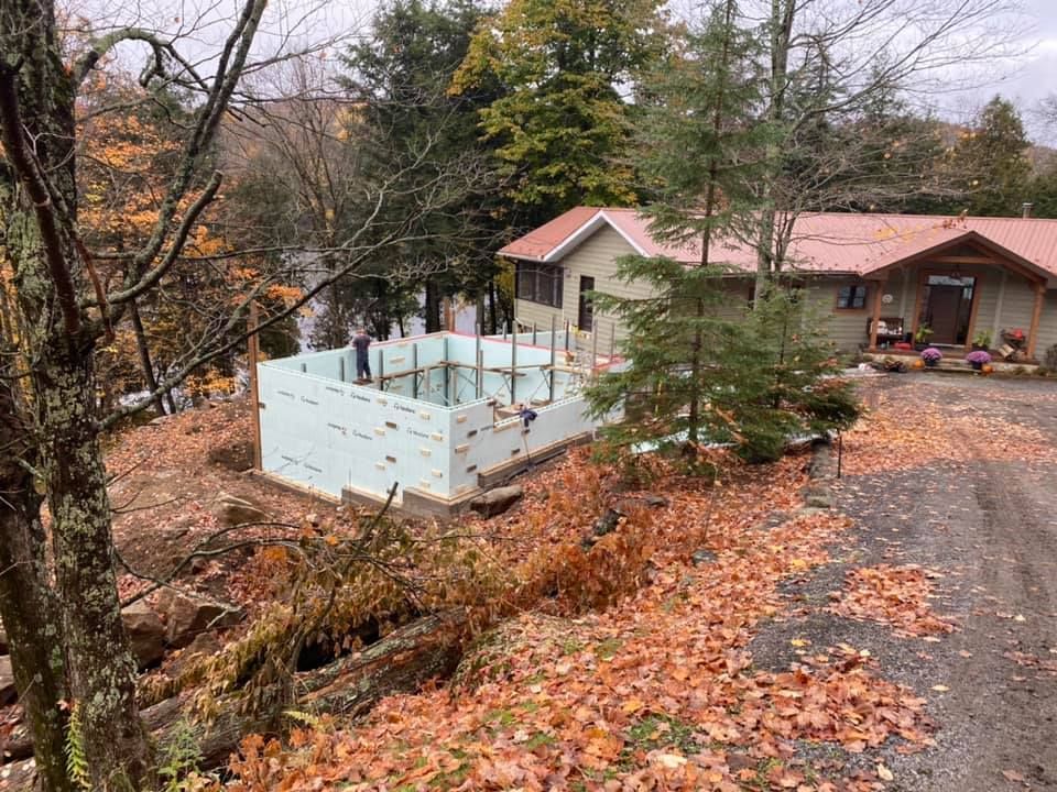 A house is being built on a hill in the woods.