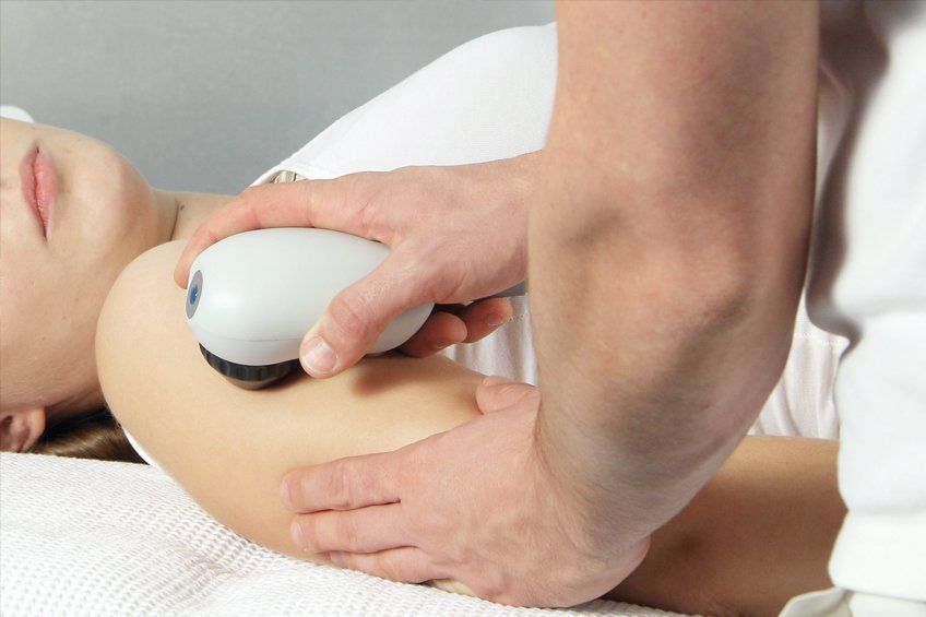 A person receiving shockwaves therapy on her arm
