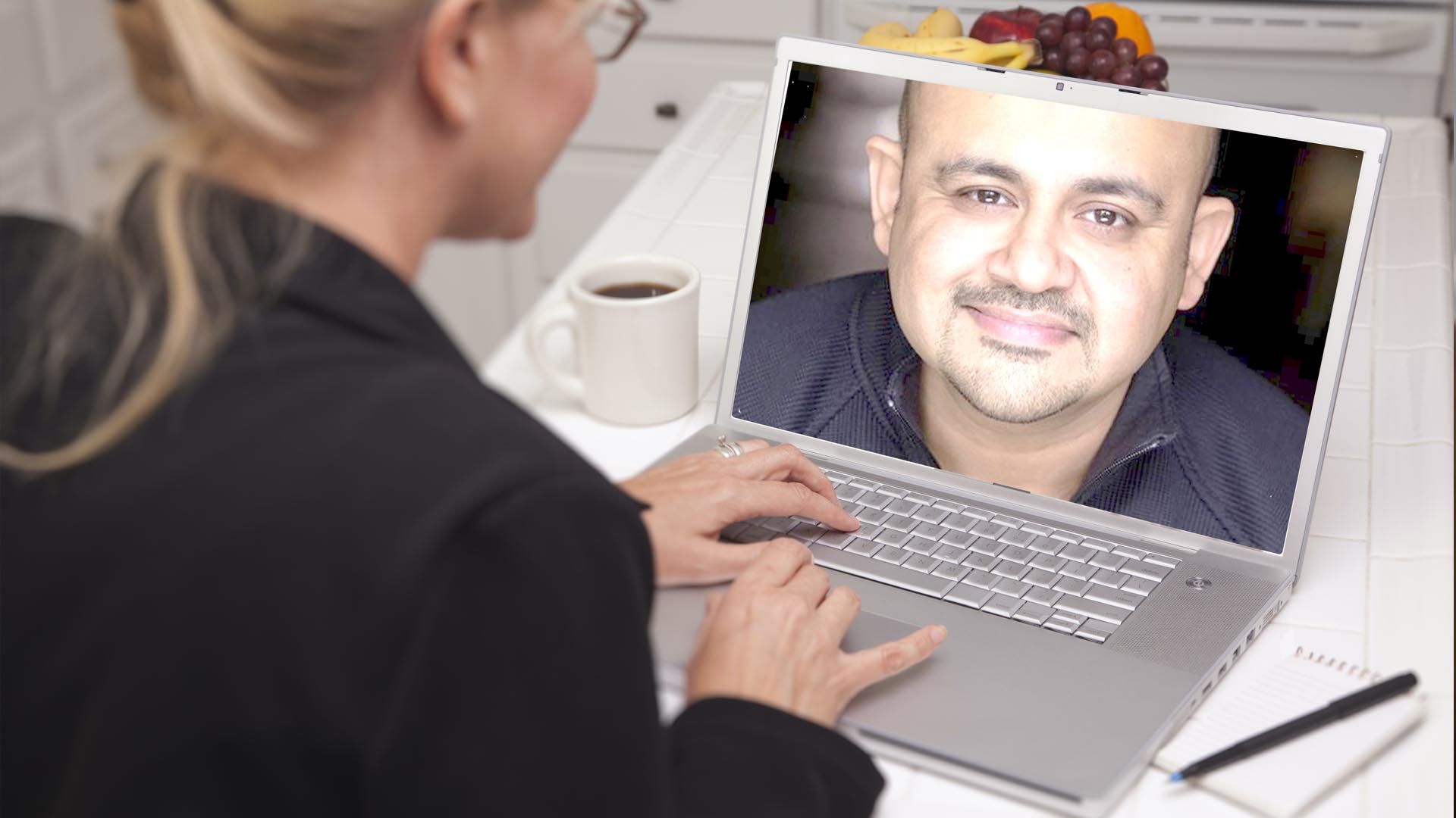 A woman is using a laptop for a virtual online consultation with Naval Mair