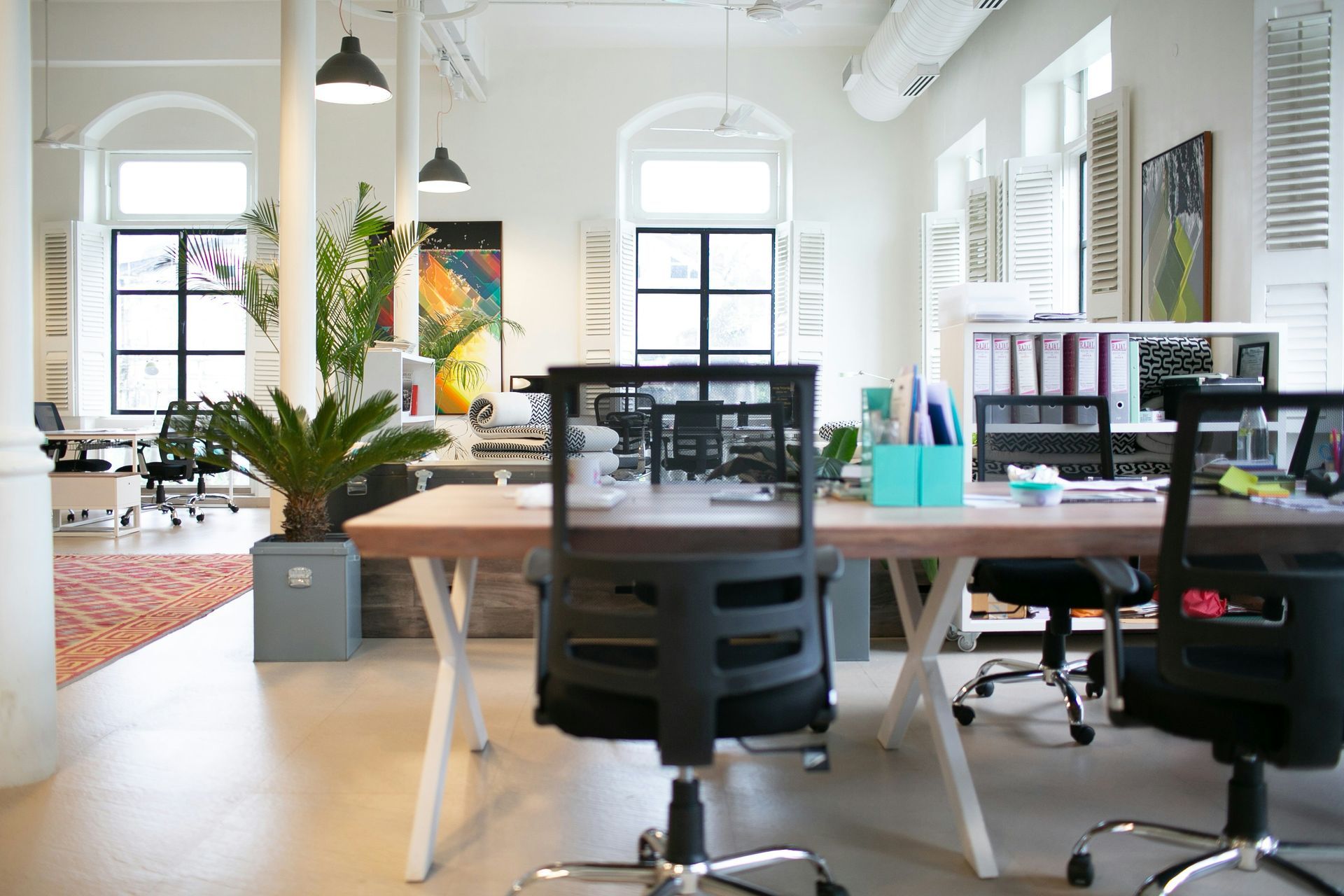 A bright office space showing several desks and office chairs.