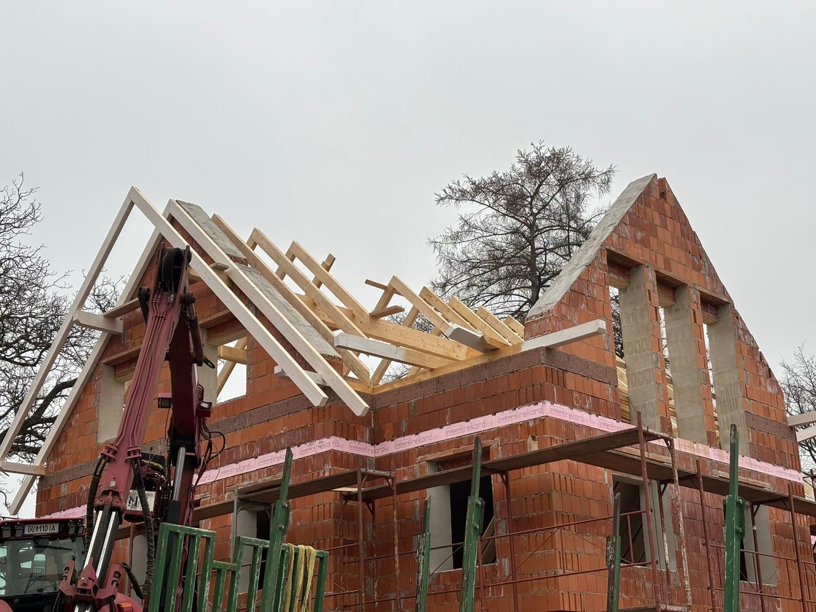 Es wird ein Backsteinhaus mit einem Holzdach gebaut.