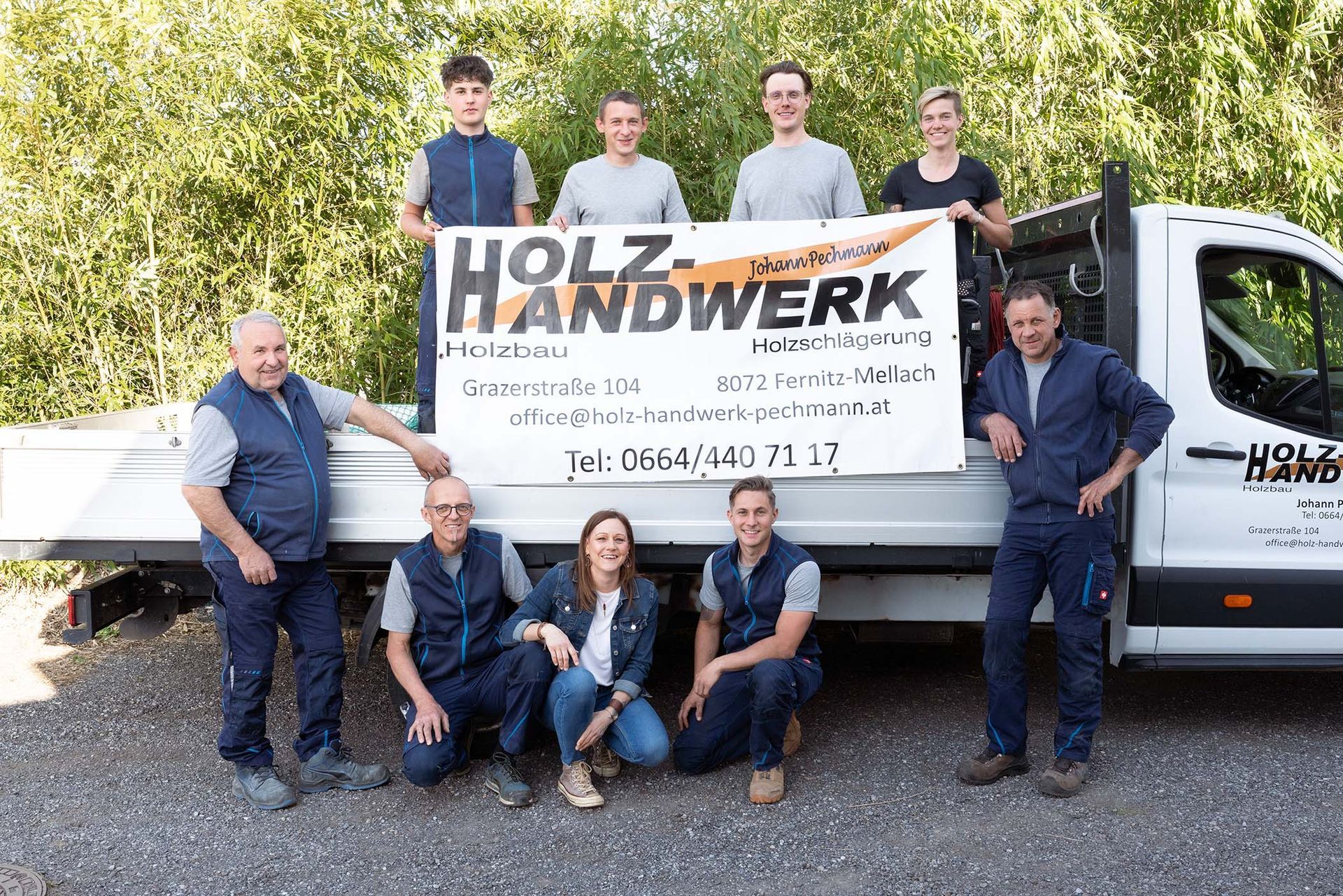 Die Mitarbeiter von Holz-Handwerk posieren vor einem Wagen für ein Foto.