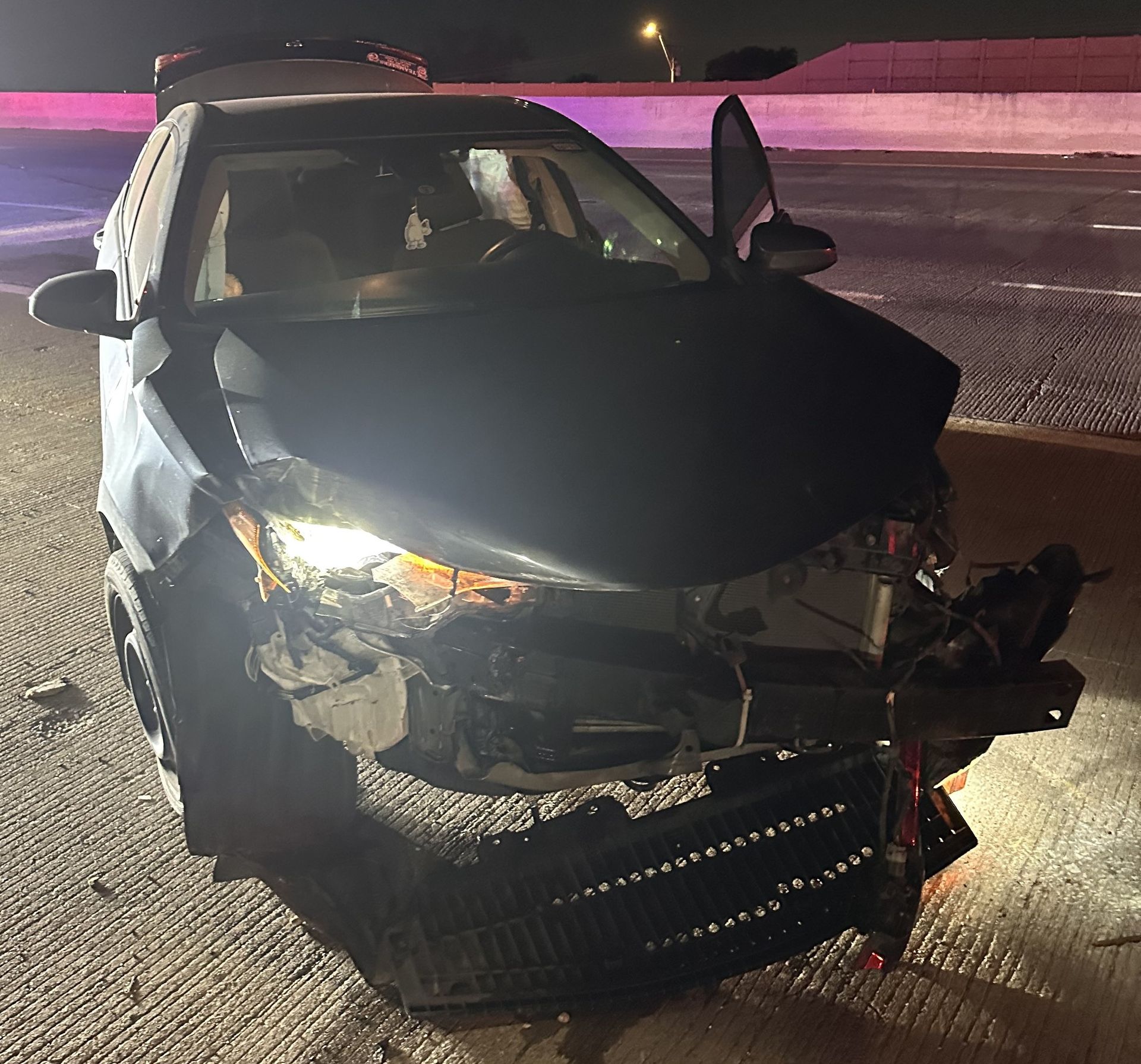Car accident victim’s sedan is crumpled and crushed on the side of 820 in Fort Worth at night