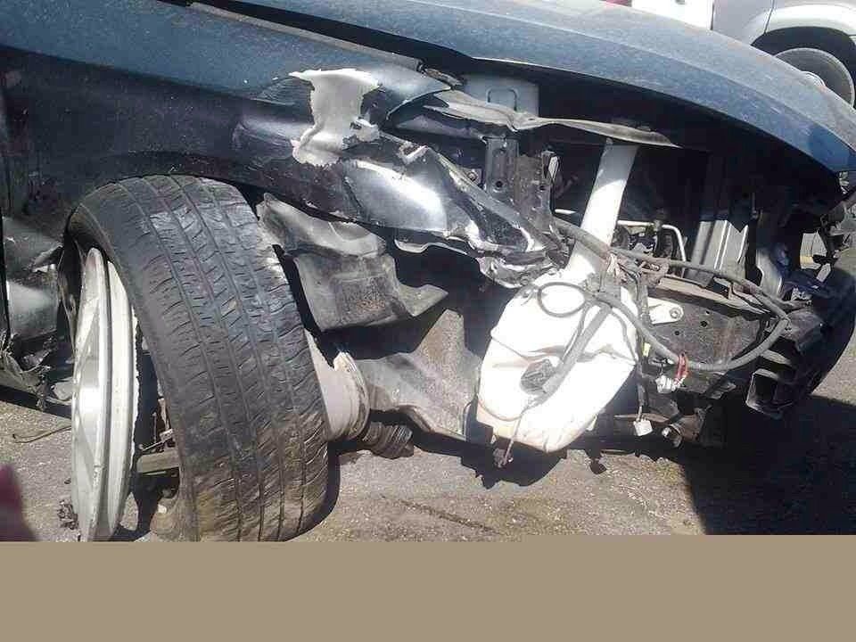 A damaged car is sitting on the side of the road.