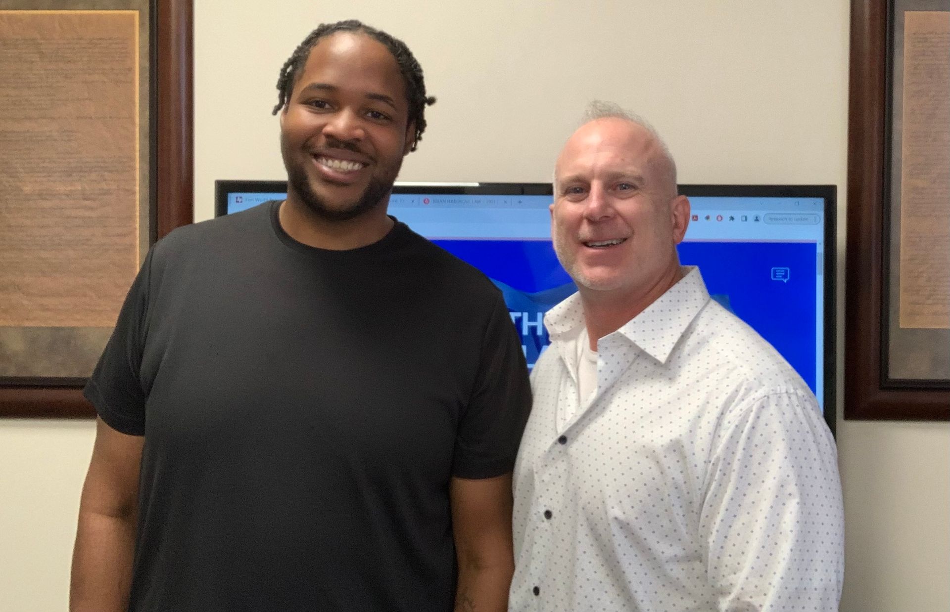 Two men are standing next to each other in front of a television