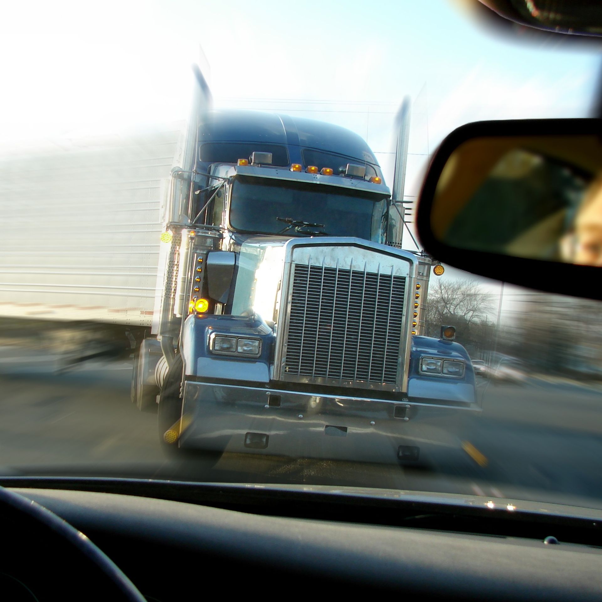Commercial truck drives straight at a person driving a car.
