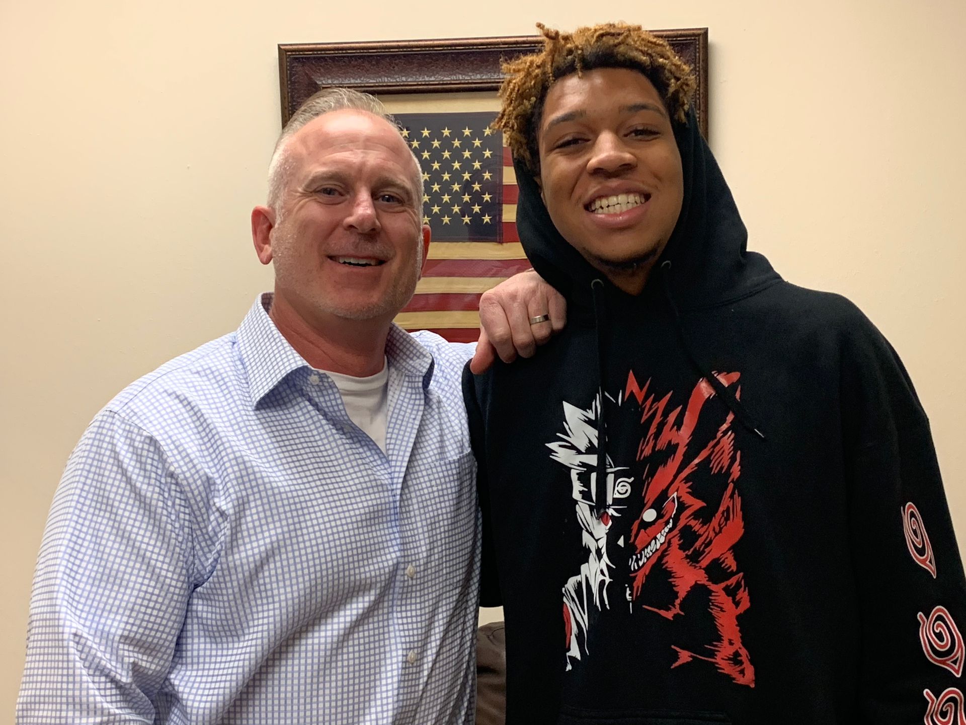 A man and a boy are posing for a picture in front of an american flag.