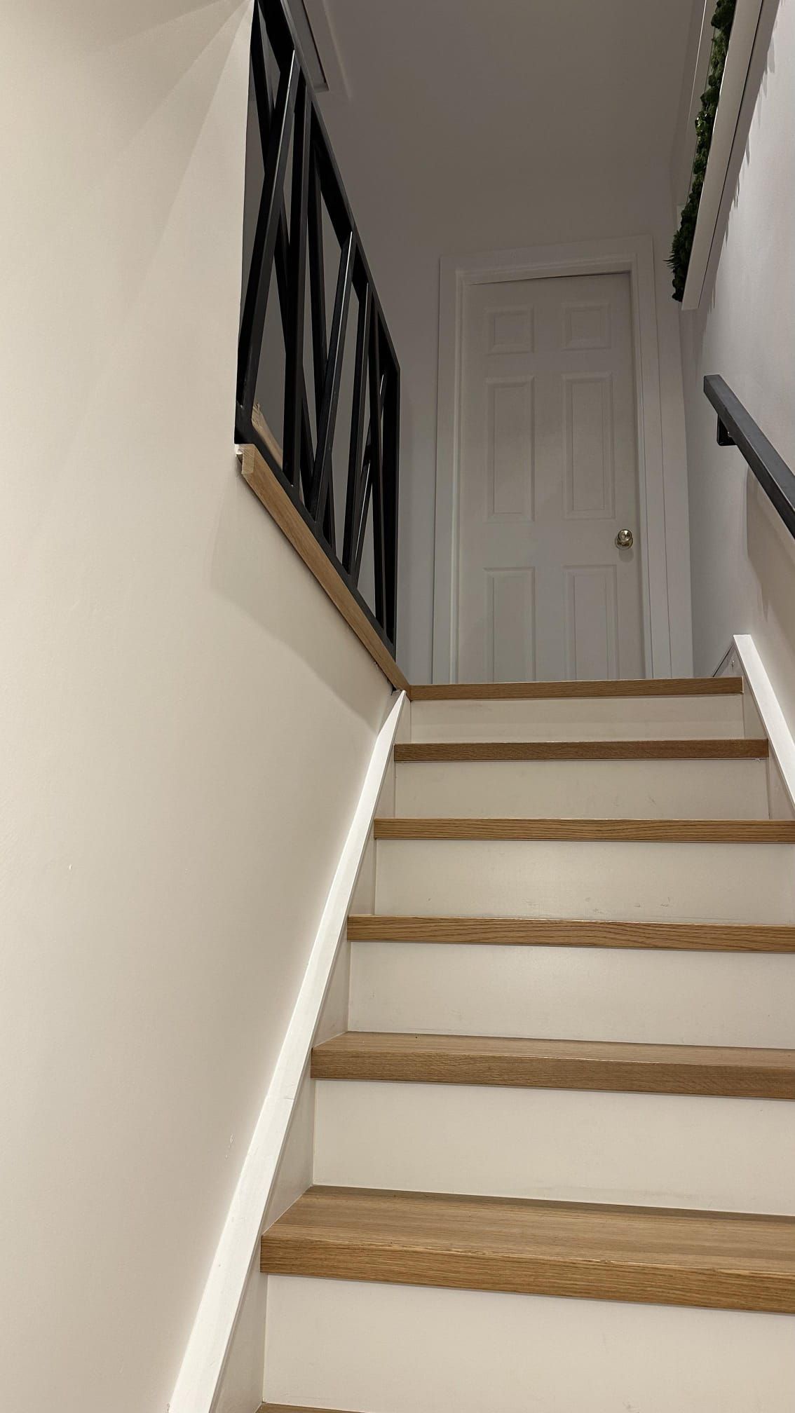A picture of a staircase painted white with a black bannister on the landing by Elite Edge Painters and Decorators Manchester.
