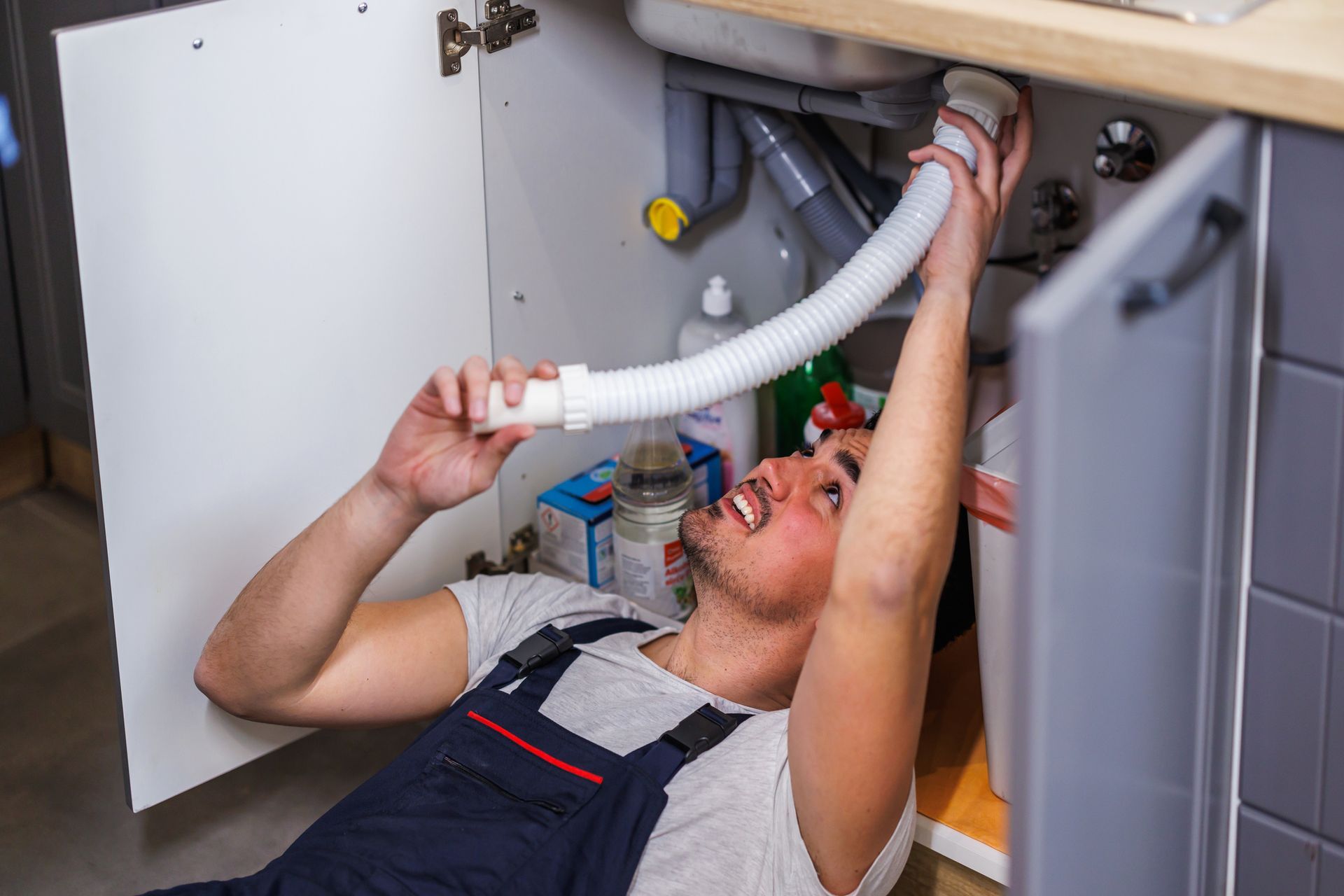 Skilled plumber repairing sink drain using professional tools with precision.
