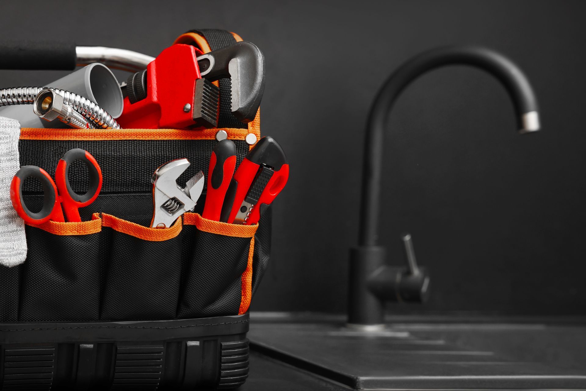 Plumber's tool bag on kitchen counter near the sink.