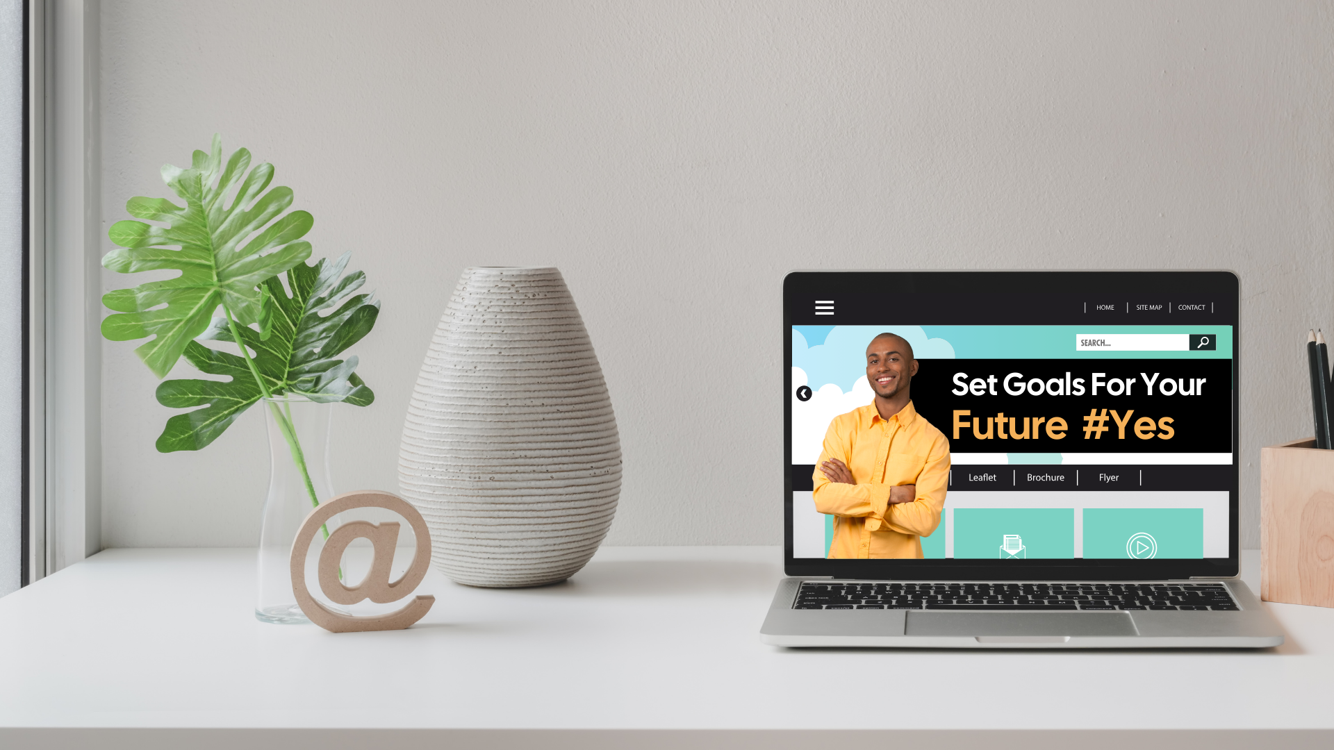 A laptop on a desk showing a website banner with the text