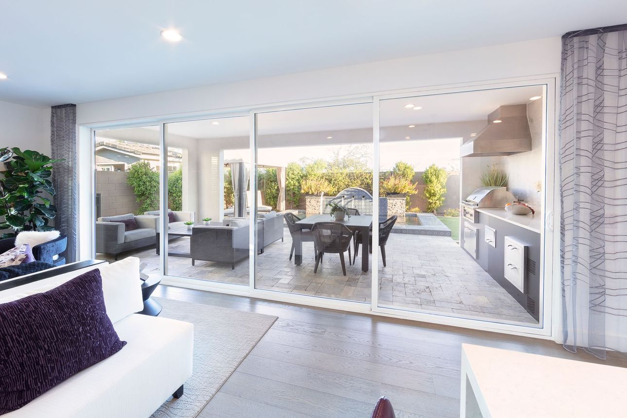 Bright modern patio room with sliding glass doors, outdoor dining table, and open garden view