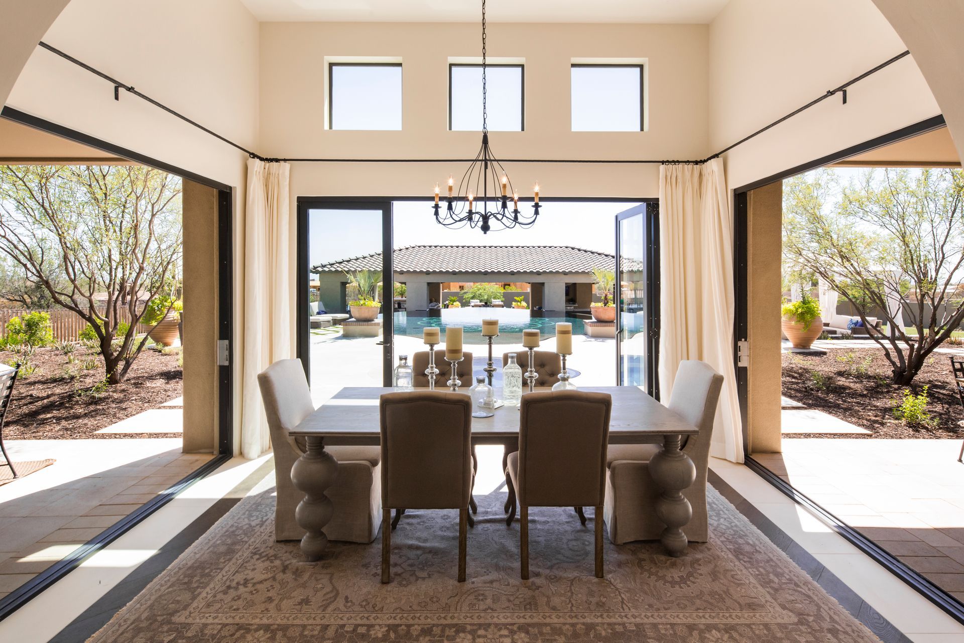 Elegant dining room opening to a sunny patio and pool through large glass doors.
