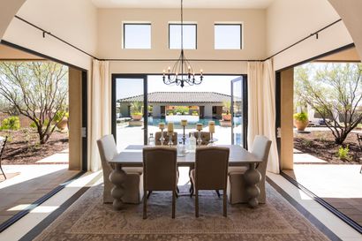 Elegant dining room with chandelier, open sliding doors, and patio view beyond modern table setting