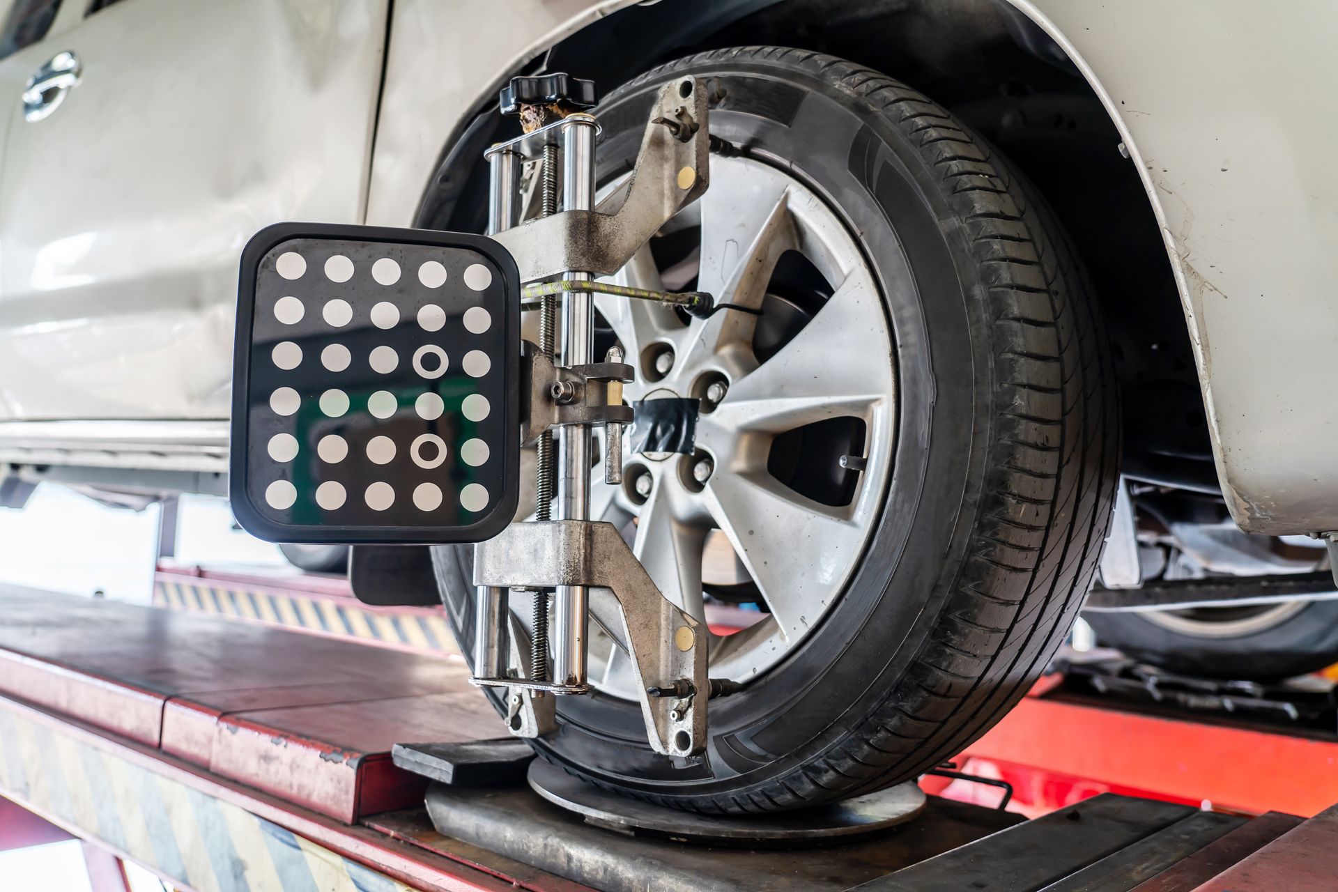 Car on wheel alignment rack with sensor rig attached to the front wheel