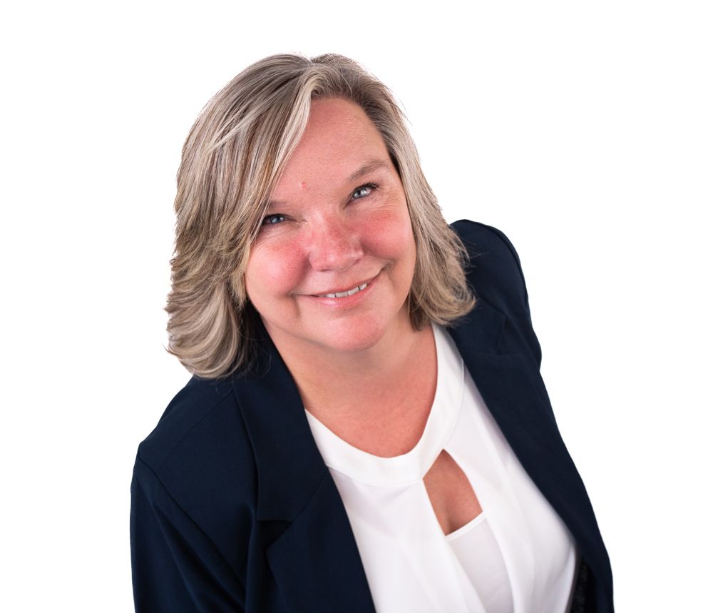 A woman wearing a blue jacket and a white shirt is smiling.