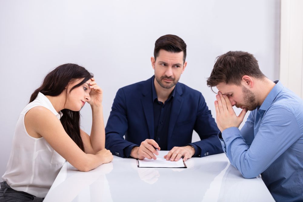 A Man and a Woman Are Sitting at a Table With a Lawyer — O'Reilly & Sochacki Lawyers in Murwillumbah, NSW