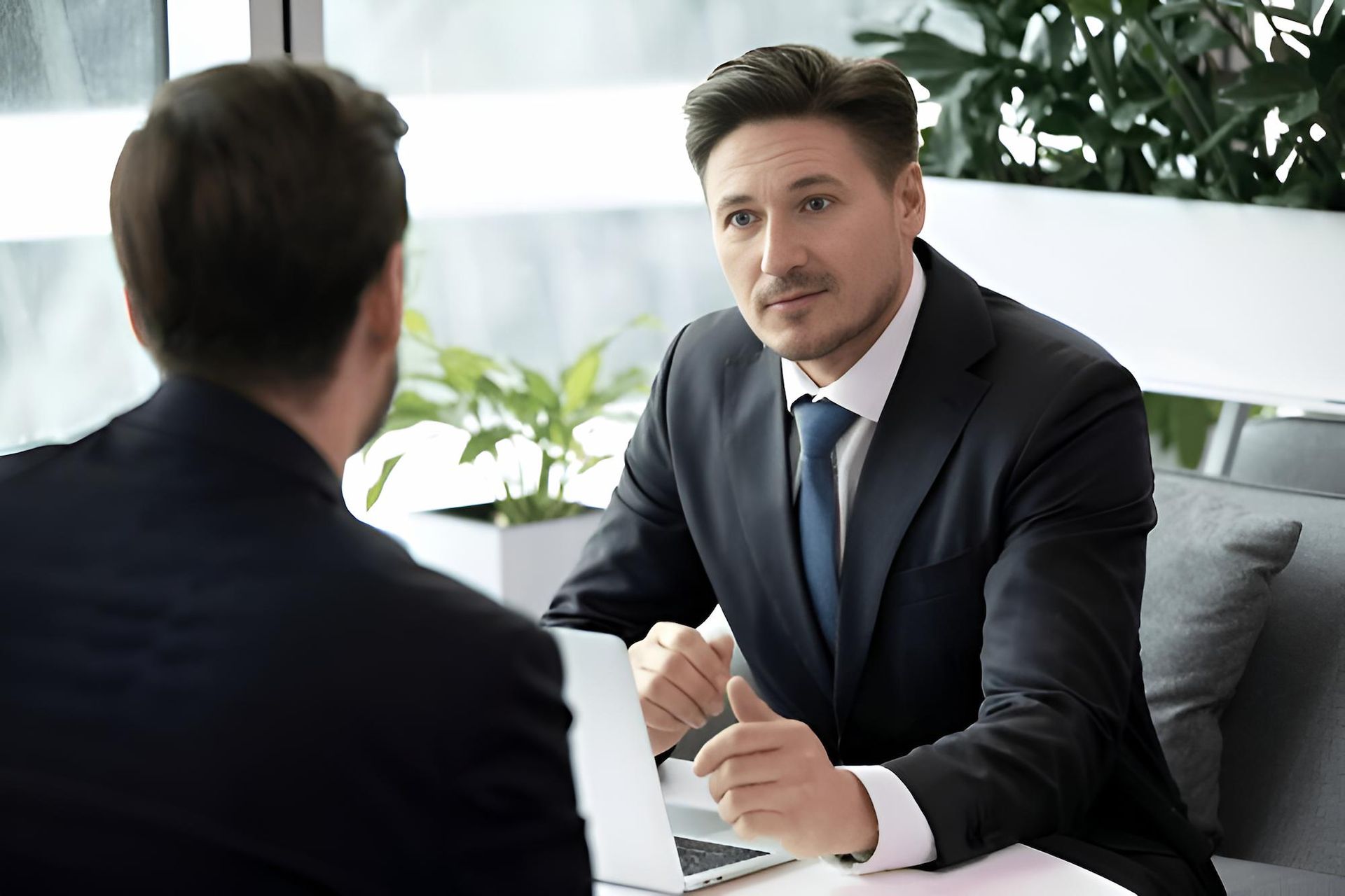 Two Men in Suits and Ties Are Sitting at a Table Having a Conversation — O'Reilly & Sochacki Lawyers in Tweed Heads, NSW