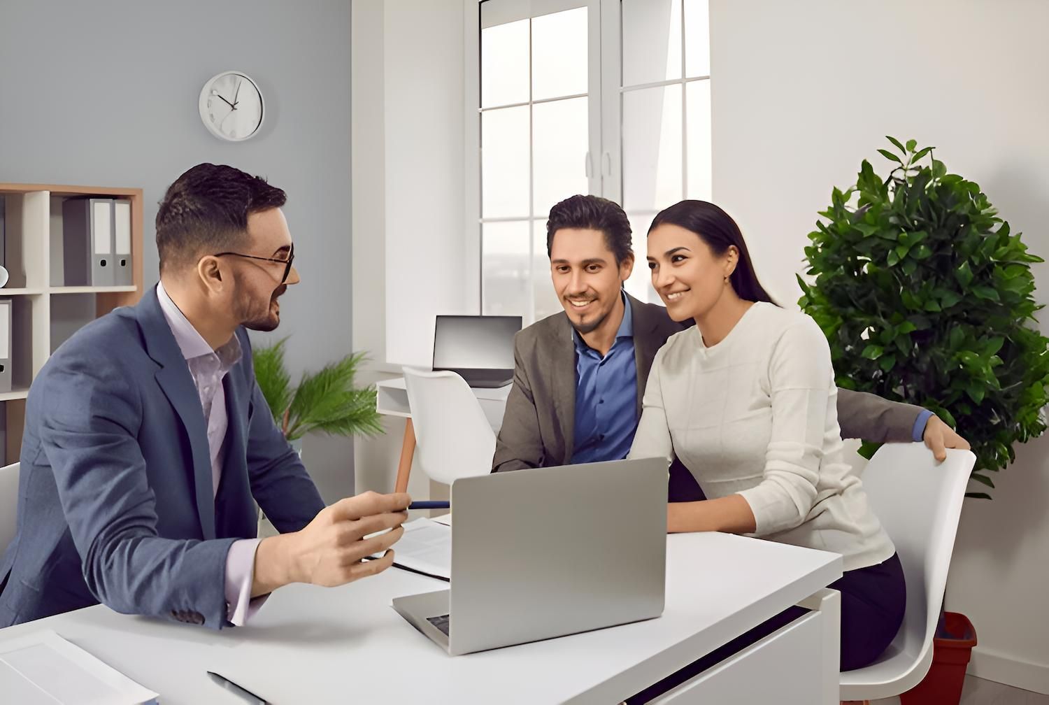 A Man is Talking to a Couple While Sitting at a Desk With a Laptop — O'Reilly & Sochacki Lawyers in Tweed Heads, NSW