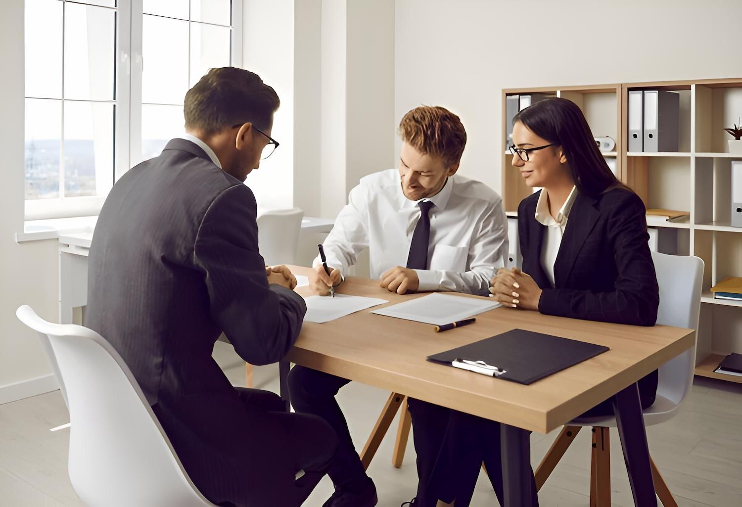 Clients Are Sitting at a Table While Signing a Document — O'Reilly & Sochacki Lawyers in Pottsville, NSW