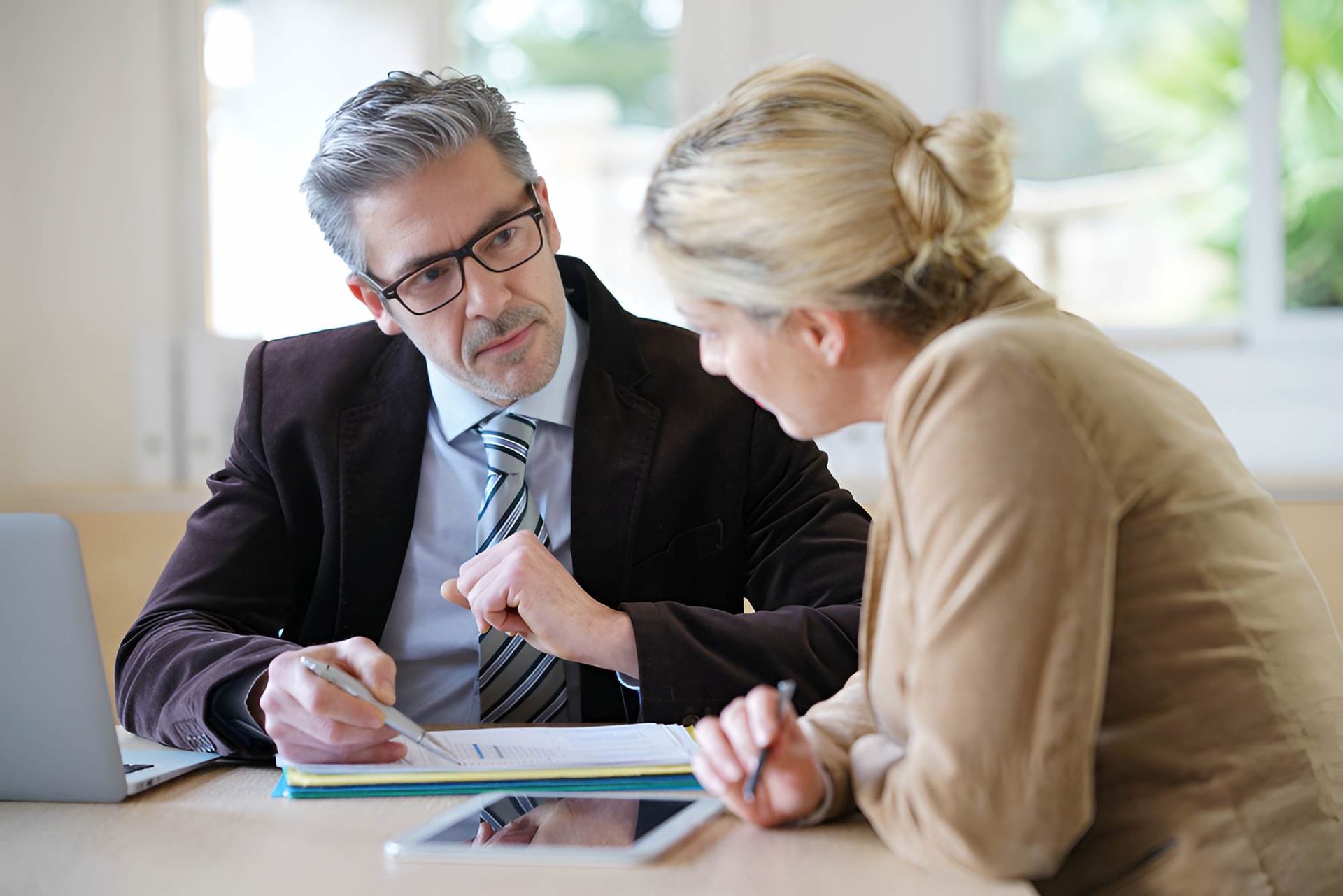 A Man and a Woman Are Sitting at a Table Looking at a Tablet — O'Reilly & Sochacki Lawyers in Pottsville, NSW