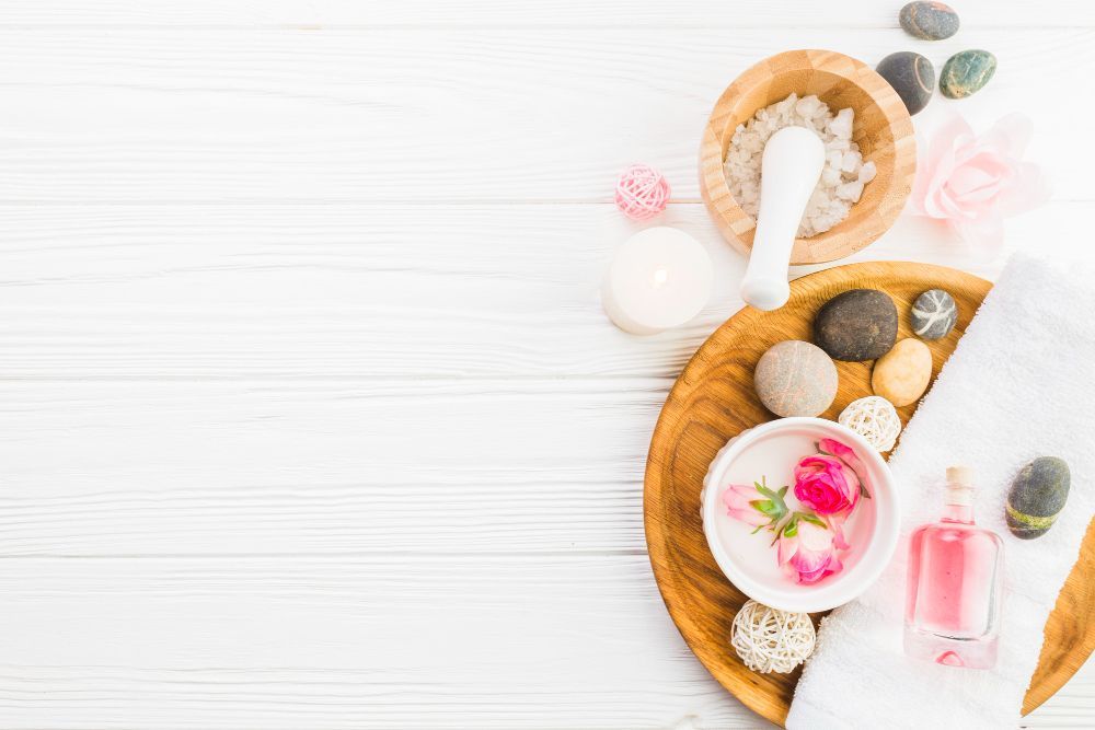 There is a bowl of water with flowers in it on a wooden tray.