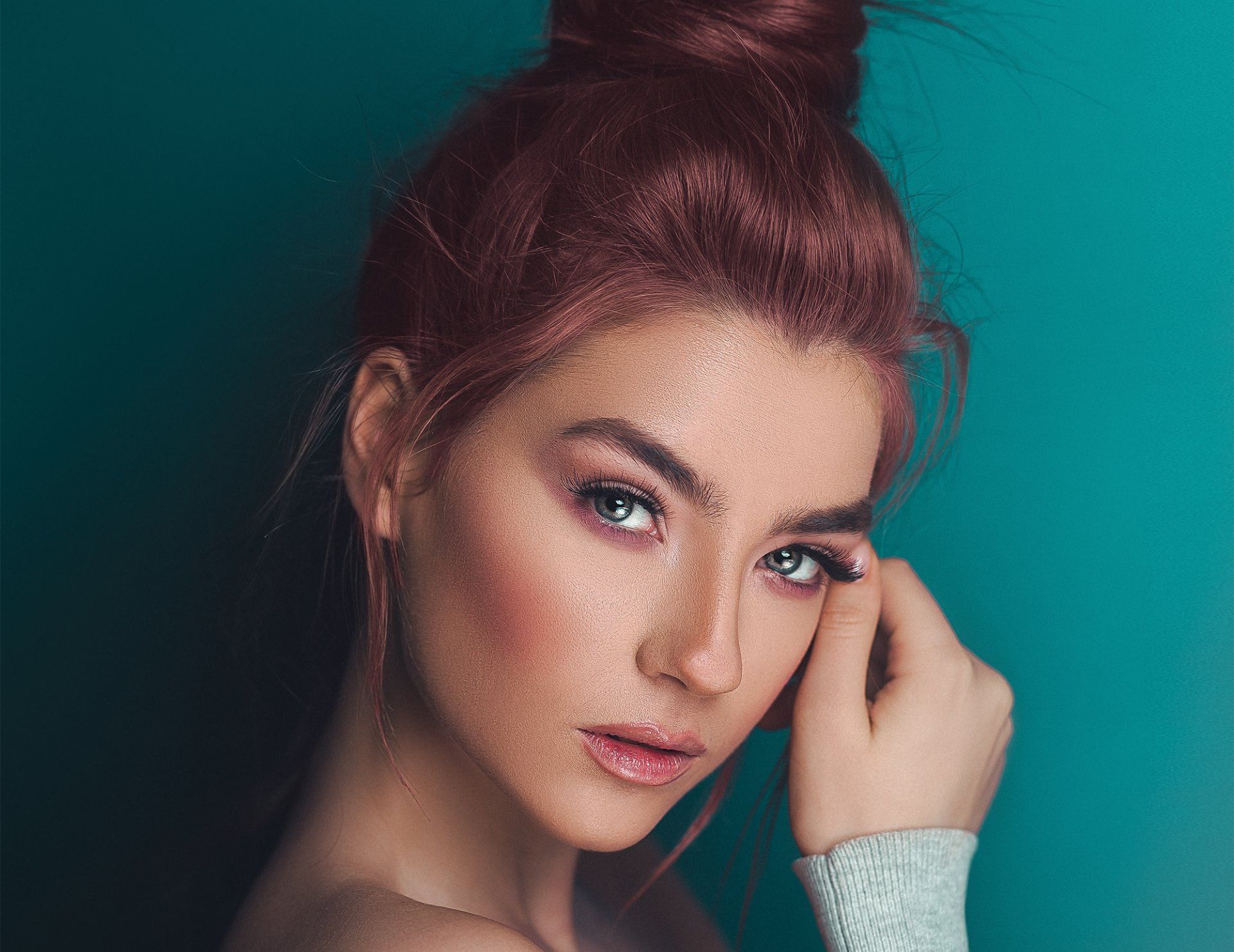 A close up of a woman 's face with red hair in a bun.