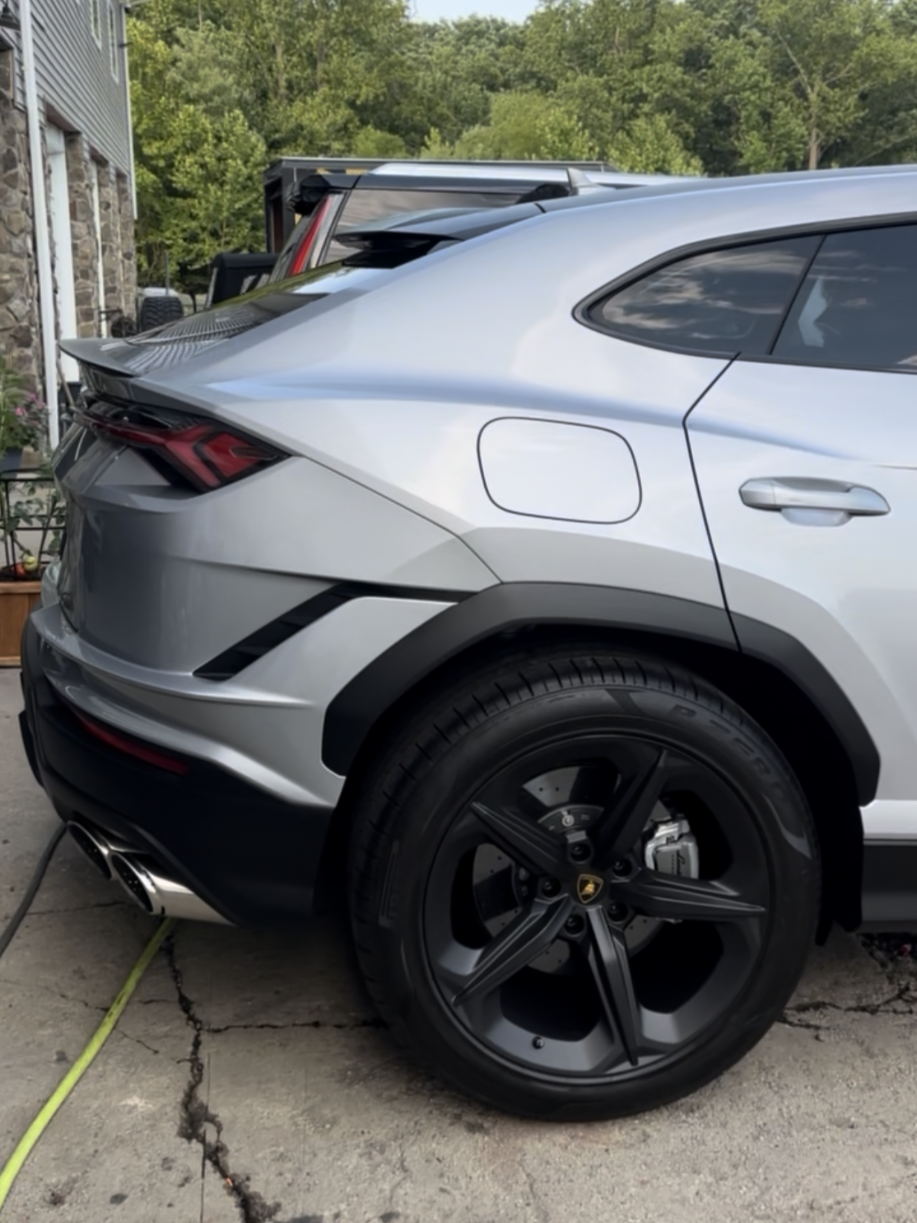 Silver Lamborghini Urus SUV with black wheels, parked outside.