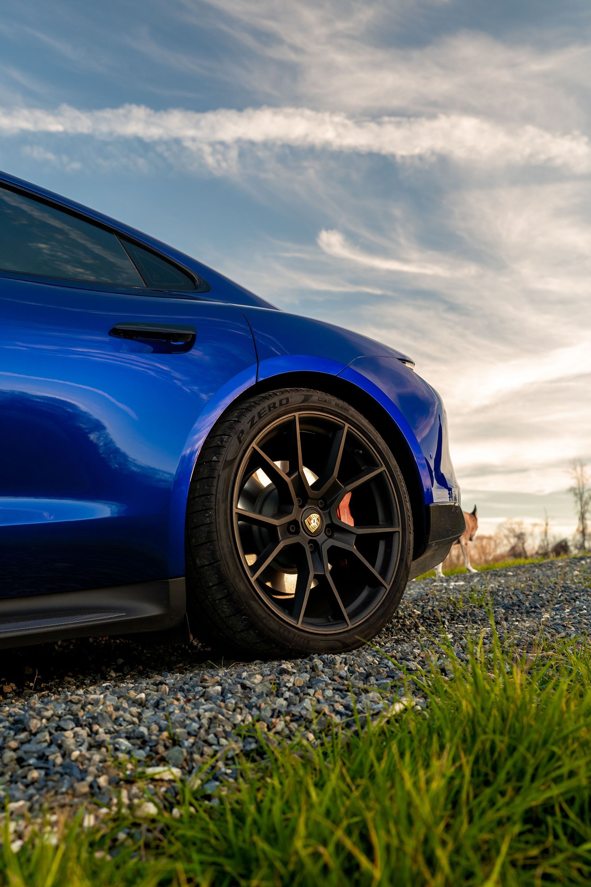 A blue sports car is parked on a gravel road.