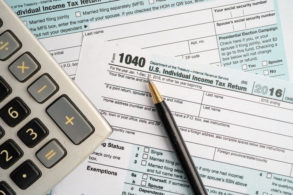 Calculator, pen, and tax form 1040 on a white surface.
