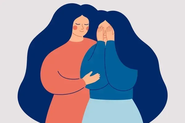 Two people hugging, one comforting the other, in coral and blue clothing against a dark blue background