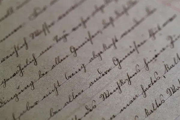 Close-up of handwritten cursive notes on aged paper, viewed at an angle.