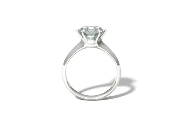 Silver solitaire engagement ring with a clear round gemstone on a white background