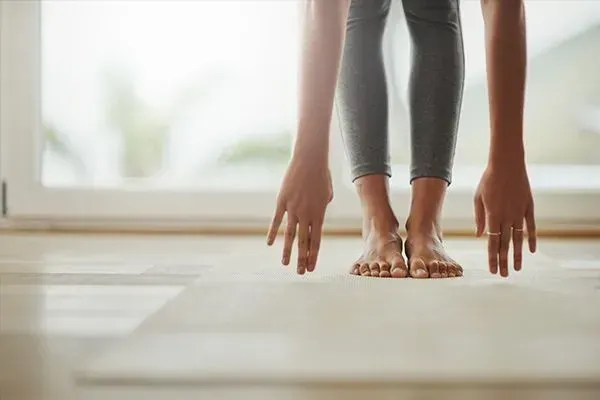 Hands and feet in yoga forward fold on a bright studio floor