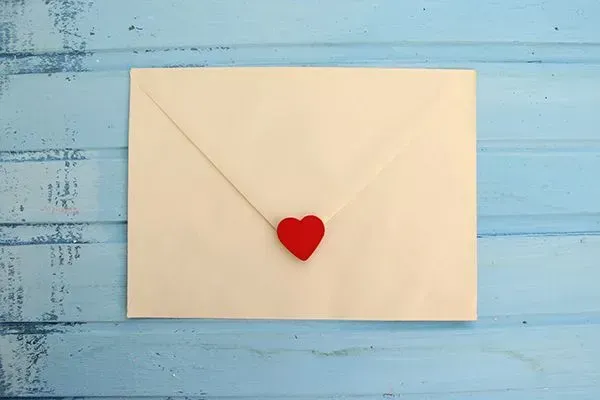 White envelope on blue wooden surface with a red heart seal