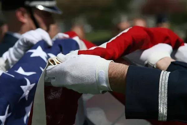 Flag-draped casket being carried by uniformed honor guards