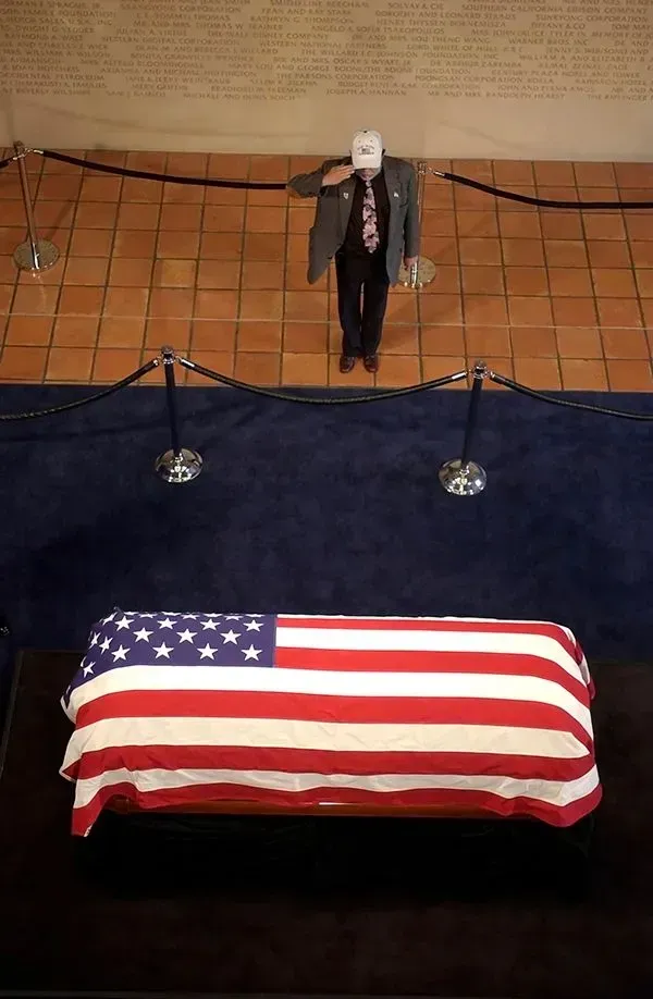 Flag-draped casket in front of a podium, suggesting a funeral or memorial service.