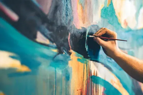 Hand painting a colorful abstract mural with a brush on a wall