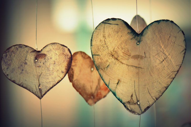 Three hanging wooden heart ornaments against a softly blurred background