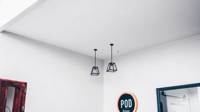 White interior room with two hanging pendant lights and a round wall sign near a doorway