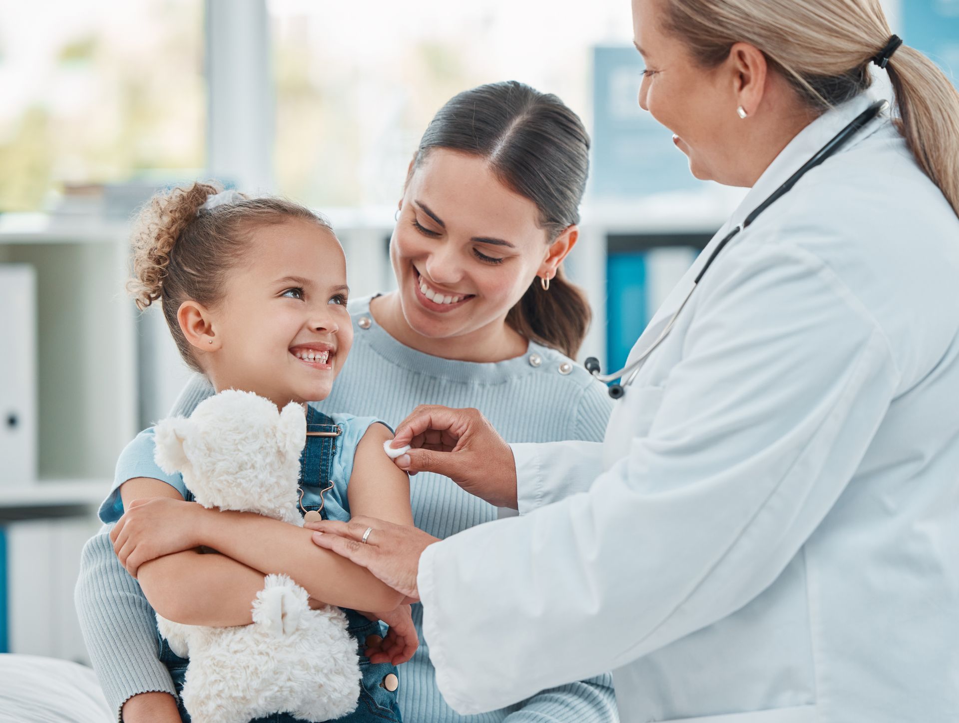 A nurse is looking at a clipboard with a little girl and a man.