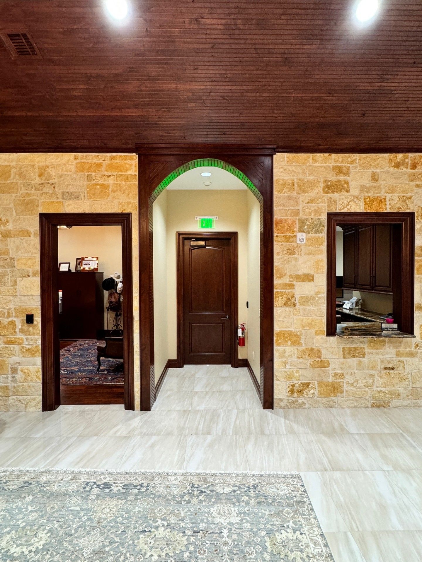 Stone-walled interior with three doorways, a central arched door, and wood ceiling panels.
